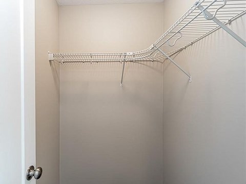 A white closet with a metal rack hanging on the wall.