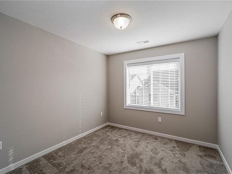 A room with a carpeted floor and a window with blinds.