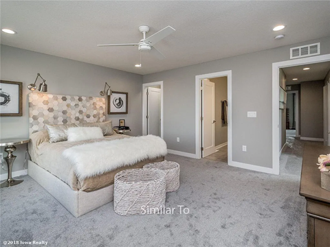 A bedroom with a large bed and a ceiling fan.