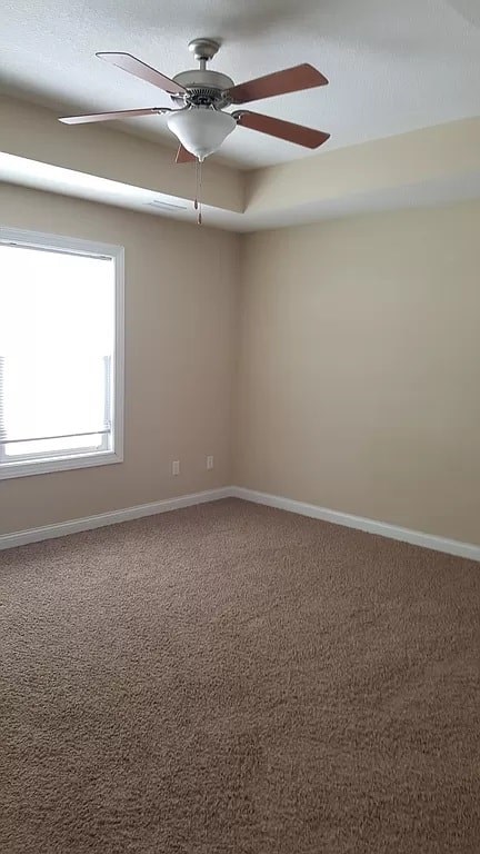 A room with a ceiling fan and carpeted floor.