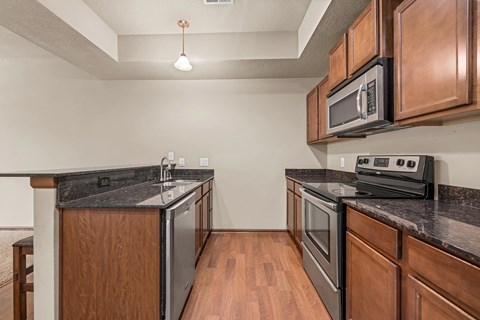 A kitchen with dark wood cabinets and black appliances.