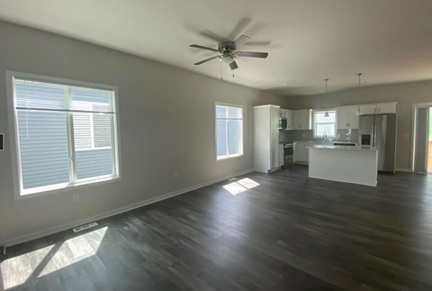 A spacious room with wooden floors and a ceiling fan.