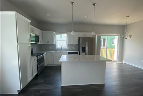 A kitchen with white cabinets and a white island.