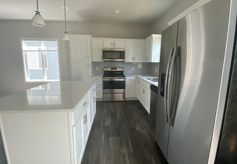 A modern kitchen with white cabinets and a stainless steel refrigerator.