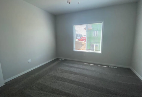 A room with a large window and a carpeted floor.