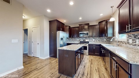 A kitchen with dark wood cabinets and a granite counter top.