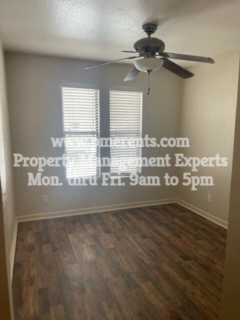 an empty living room with a ceiling fan