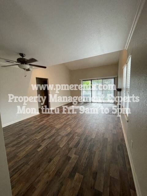 an empty living room with a ceiling fan and wood floors