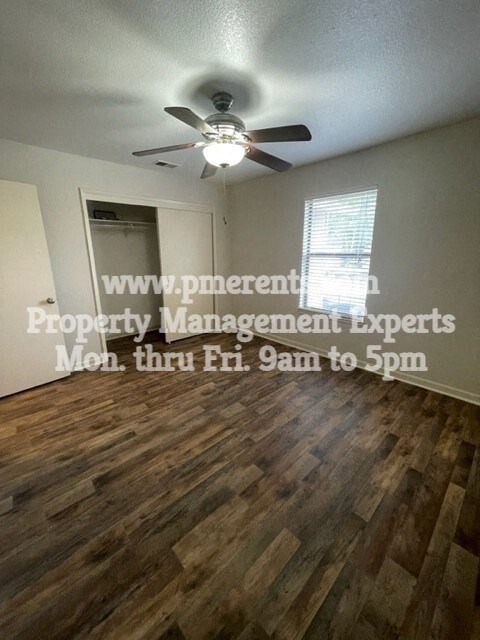 an empty living room with a ceiling fan and wood floors