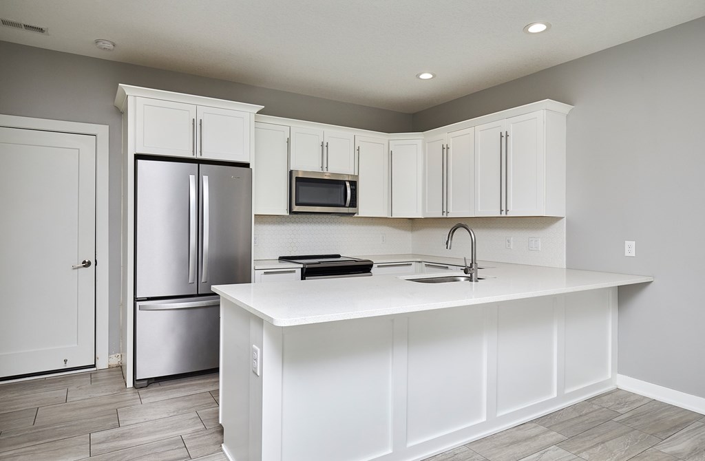 A kitchen with white cabinets and a white island.