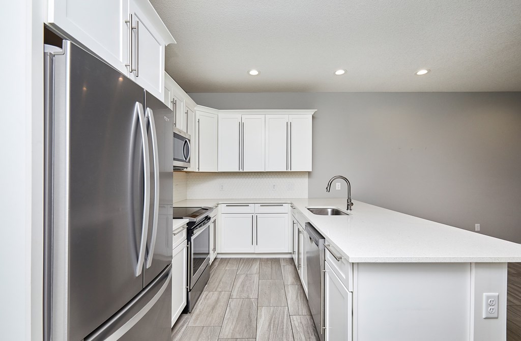A modern kitchen with white cabinets and a stainless steel refrigerator.