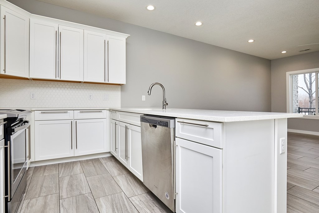 A modern kitchen with white cabinets and a stainless steel dishwasher.