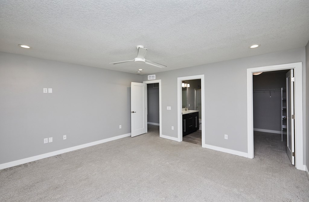 A spacious room with a ceiling fan and carpeted floor.
