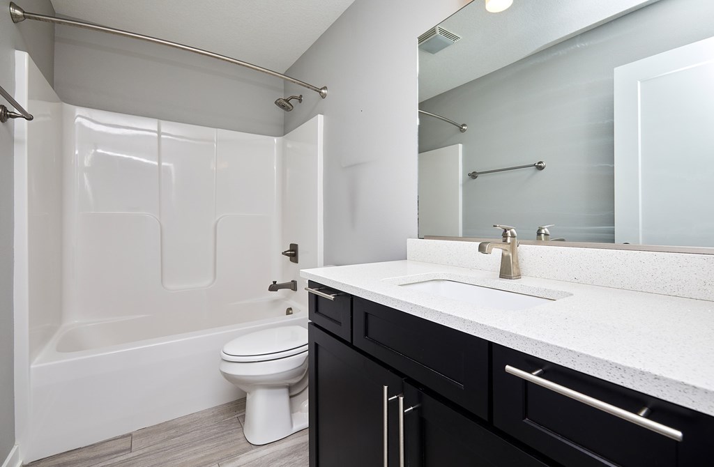 A white toilet sits in a bathroom with a black vanity.