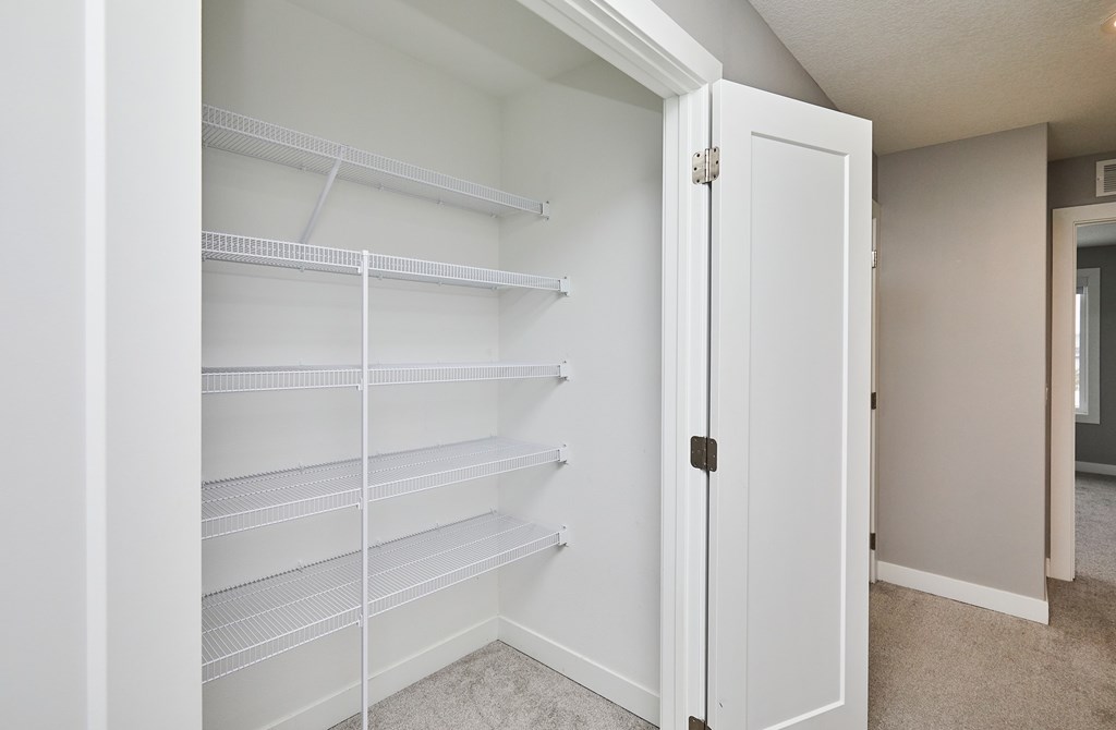 A white pantry with a white door is open.