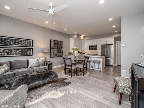 A modern living room with a grey couch and a dining table set up.
