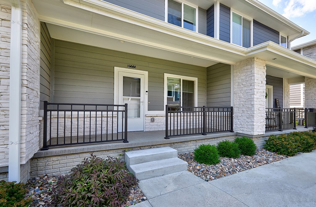 A house with a front porch and a black railing.
