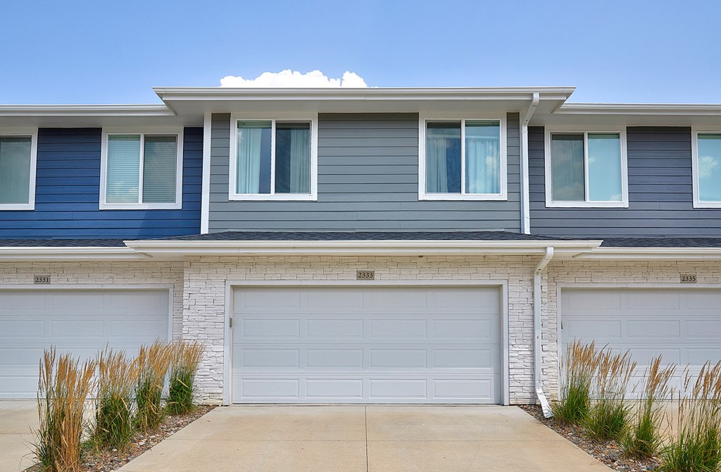 A house with a white garage door and a blue house above it.