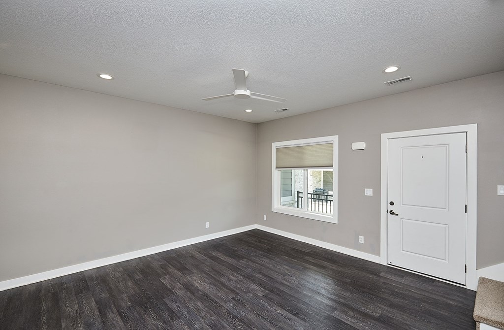 A room with a white door and a window with a view of a balcony.