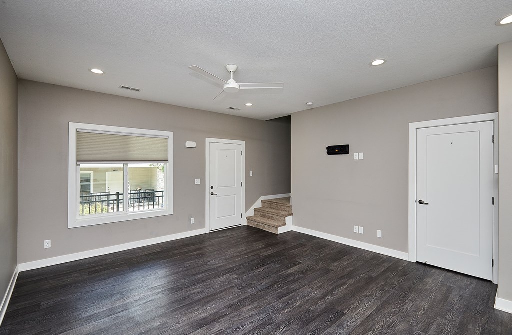 A spacious room with a ceiling fan and a window overlooking a balcony.