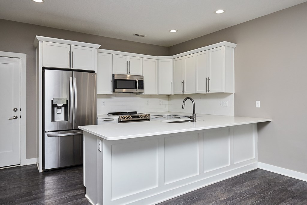 A kitchen with white cabinets and a stainless steel refrigerator.