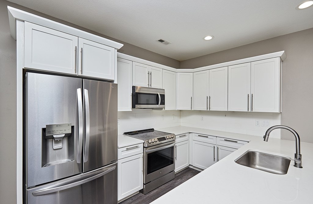 A modern kitchen with white cabinets and stainless steel appliances.