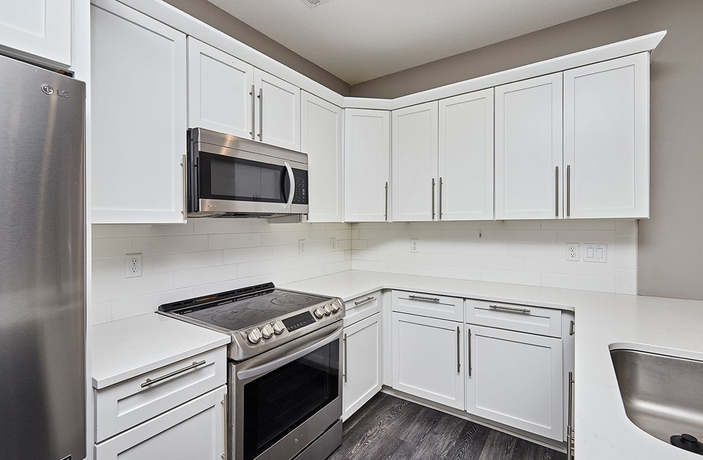 A kitchen with white cabinets and a stainless steel refrigerator.