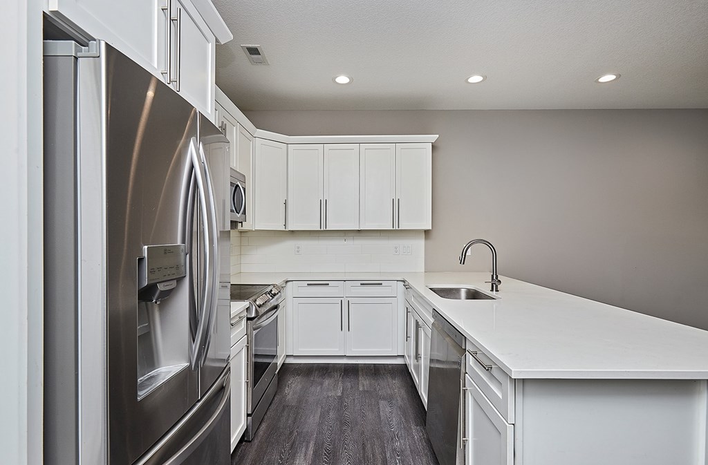 A modern kitchen with white cabinets and a stainless steel refrigerator.