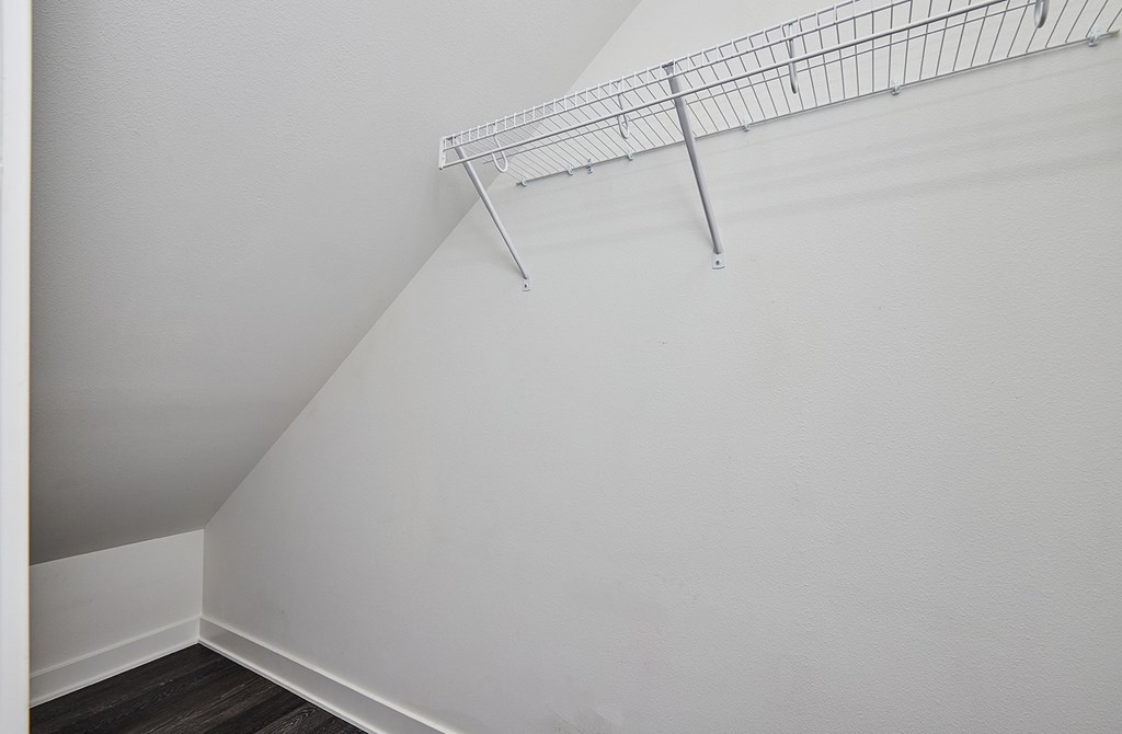 A white wall with a metal shelf attached to it.