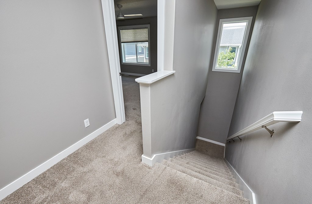 A stairway with a carpeted floor and a white railing.