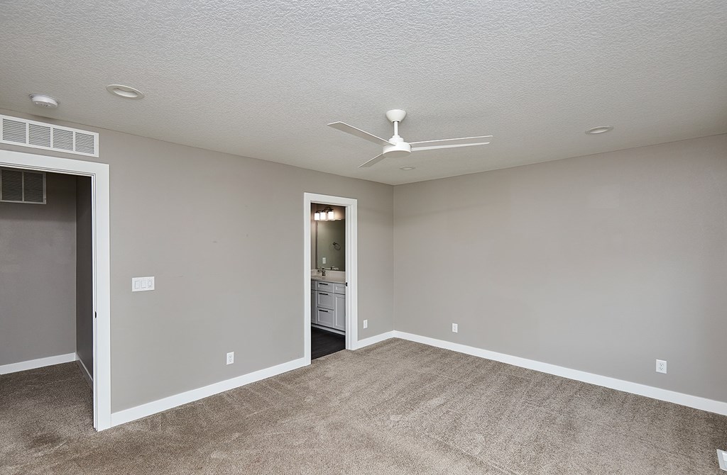 A room with a ceiling fan and carpeted floor.