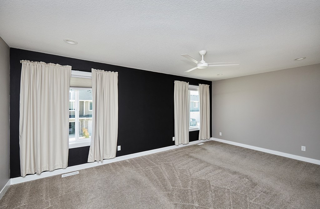 A room with a carpeted floor and a ceiling fan.