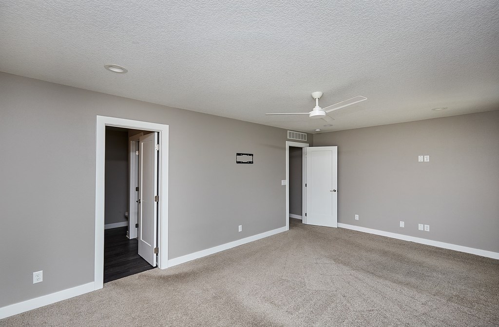 A room with a carpet floor and a ceiling fan.