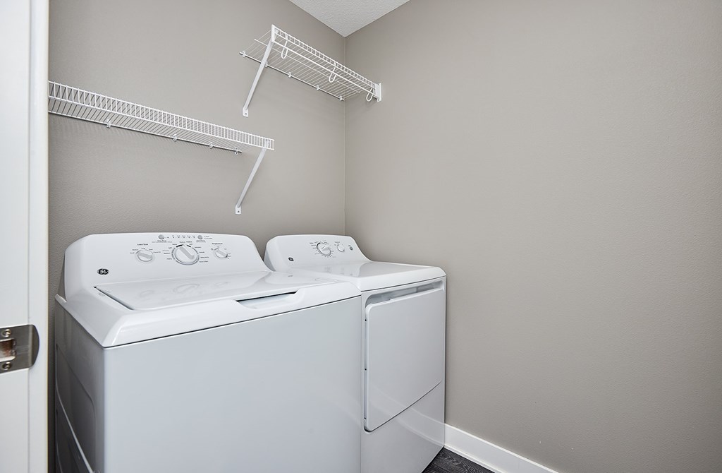 A white dryer is in a laundry room with a white door.