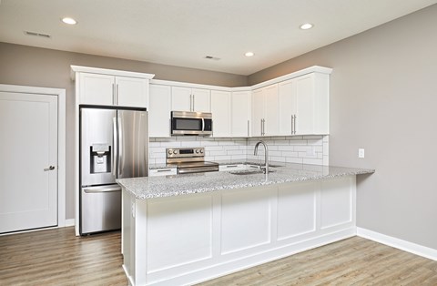 A kitchen with white cabinets and a granite countertop.