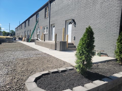 A grey building with a small tree in front.