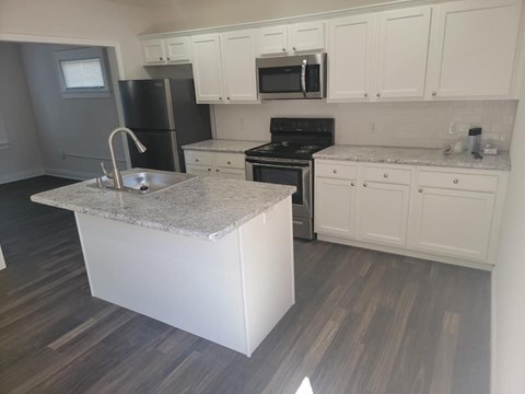 A kitchen with a granite island and white cabinets.