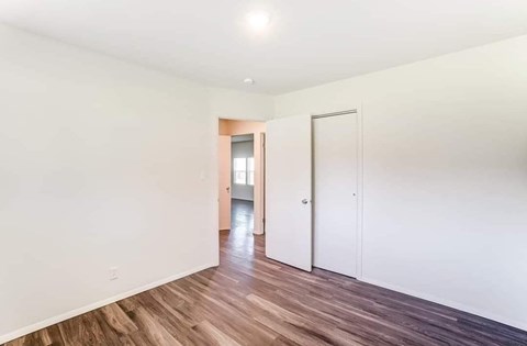 A room with a white wall and a wooden floor.