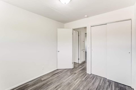 A room with a white door and a grey floor.