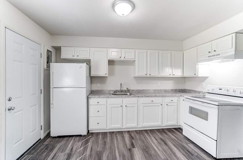 A white kitchen with a refrigerator, oven, and cabinets.