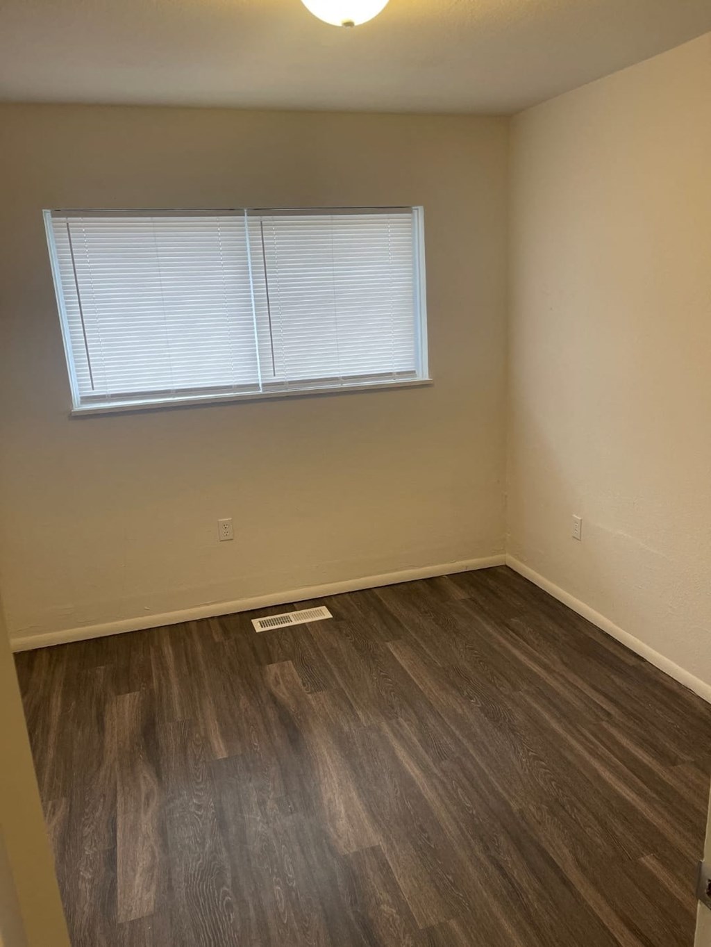 an empty room with a window and wooden floors