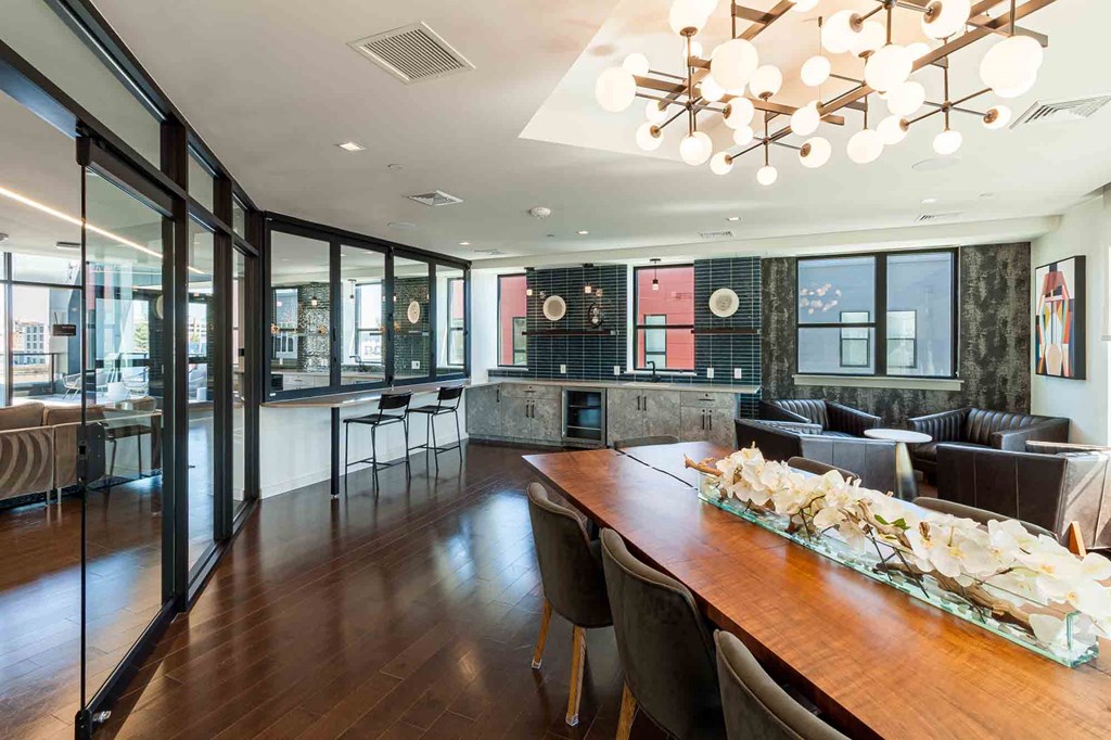 A long wooden table is surrounded by chairs in a room with a black and white patterned wall.