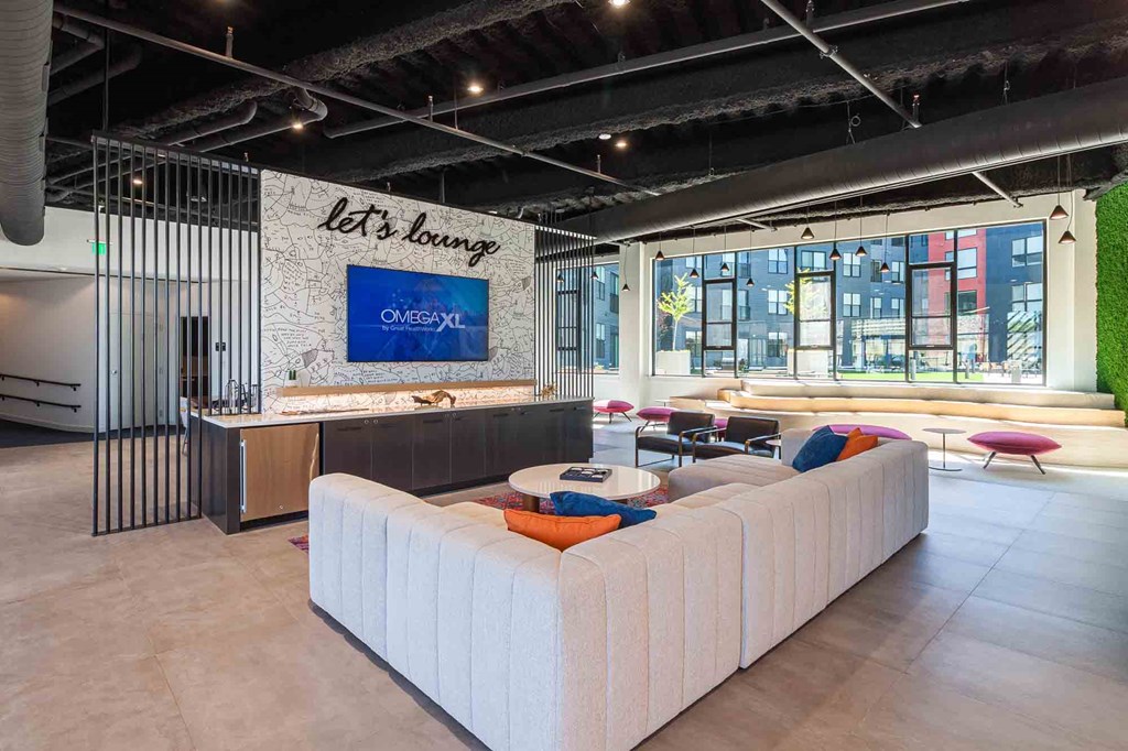 A white couch is in the middle of a room with a blue sign that says "Let's lounge" on the wall.