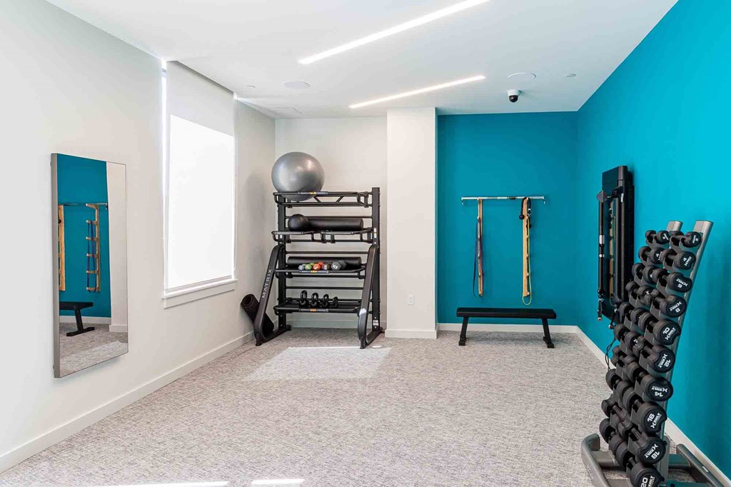 A room with a blue wall and a gym set up with weights and a bench.