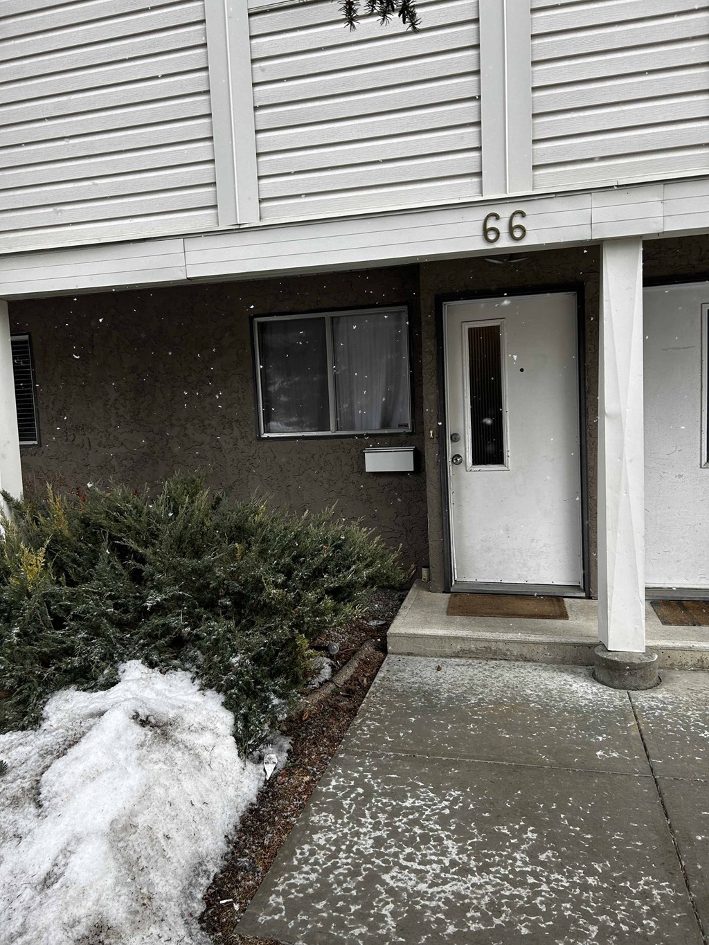 a house with a white door and a sidewalk in the snow