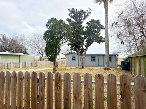 a backyard with a fence and a house in the background