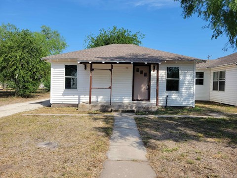 a small white house with a sidewalk in front of it