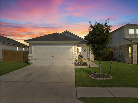 a house with a driveway and a sunset in the sky