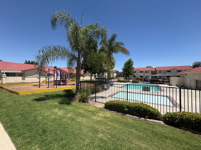 A pool surrounded by a black fence and a green lawn.