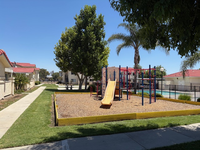 A playground with a yellow slide and a red and blue swing set.